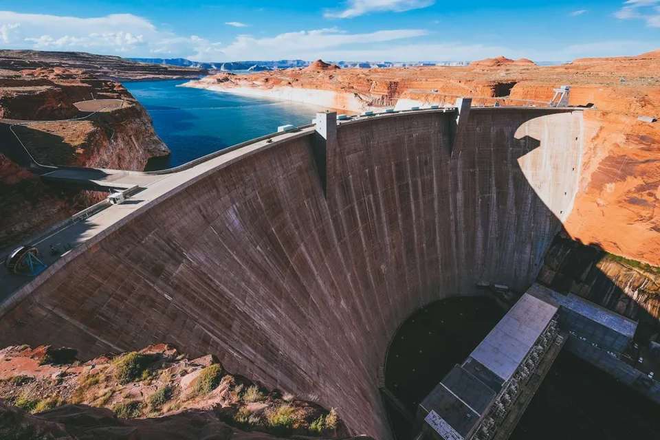 Concrete dam holding a reservoir in a sandstone canyon.